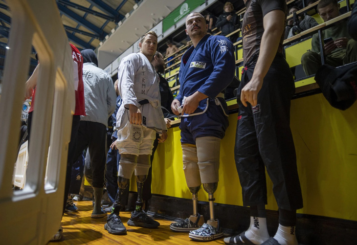 Những người tập tán gẫu và giúp đỡ nhau thắt lại đai kimono trước khi trận đấu bắt đầu - Ảnh: AP News