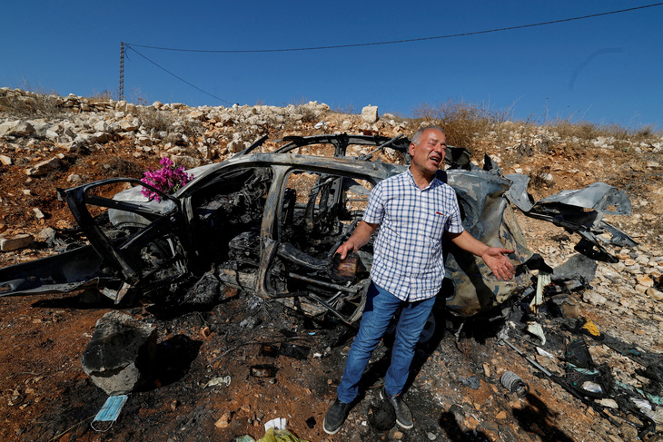 Thân nhân của những người thiệt mạng trong một cuộc không kích của Israel đứng bên cạnh chiếc xe bị đốt cháy gần biên giới Lebanon và Israel ở ngoại ô thị trấn phía nam Aynata, Lebanon ngày 6-11 - Ảnh: REUTERS