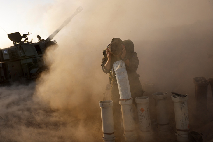 Một người lính ẩn nấp khi một đơn vị pháo binh khai hỏa gần biên giới Dải Gaza ở Israel, ngày 6-11 - Ảnh: REUTERS