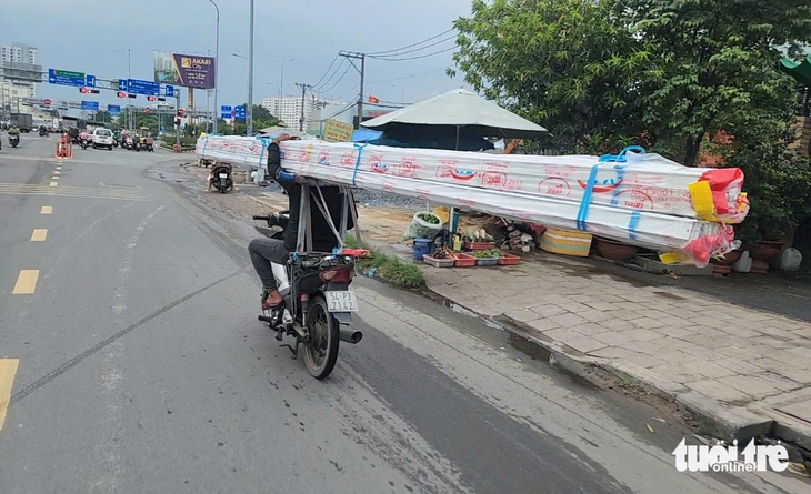 Nam thanh niên chở các thanh nhôm dài ngoằng, cồng kềnh trên xe máy ở đường An Dương Vương (quận Bình Tân) - Ảnh: NGỌC KHẢI