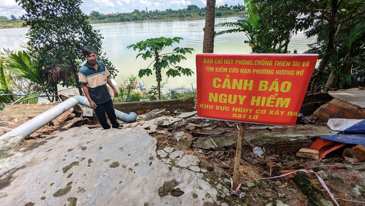 Anh Nguyễn Văn Vĩnh  - trú phường Hương Hồ, TP Huế - nói rằng mỗi bận mưa bão là chính quyền lại đến cắm biển, giăng dây cảnh báo sạt lở trước căn nhà của anh - Ảnh: NHẬT LINH