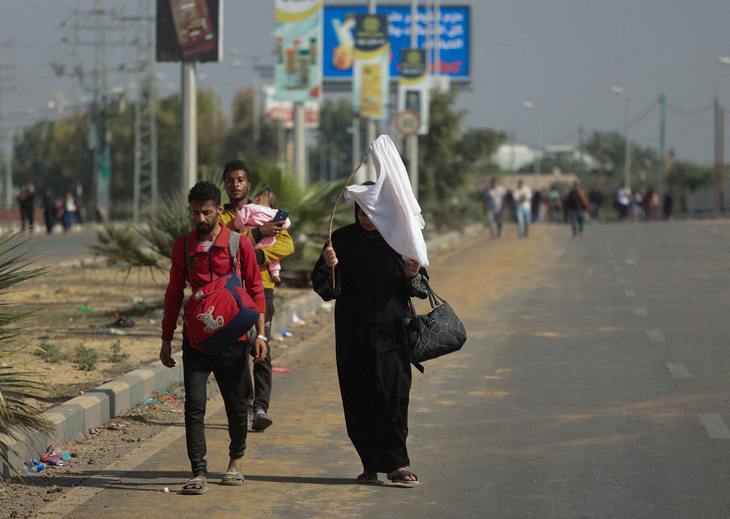 Một người phụ nữ Palestine cầm cờ trắng, cùng một nhóm dân thường di tản từ phía bắc xuống phía nam Dải Gaza ngày 7-11 - Ảnh: REUTERS