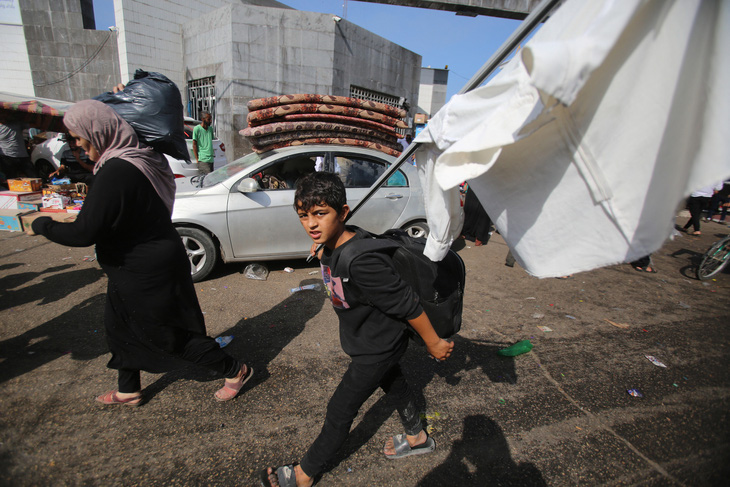 Một cậu bé Palestine cầm cờ trắng theo mẹ chạy khỏi thành phố Gaza  - Ảnh: AFP