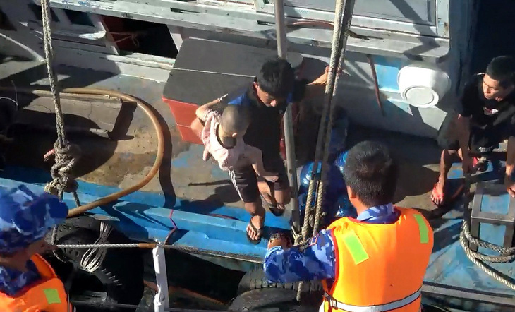 Người lớn bồng bé trai 3 tuổi từ tàu bị nạn sang tàu cảnh sát biển - Ảnh: Cảnh sát biển cung cấp