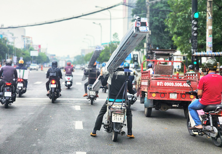 Hai người đi trên hai xe máy chở nhiều thanh kim loại dài ngoằng trên đường Tên Lửa (quận Bình Tân), chiều 7-11 - Ảnh: NGỌC KHẢI