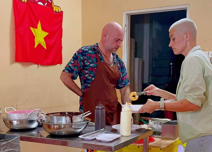 Anh Andrei Abramov (trái) và chị Valeriia Kuropatkina đang làm bánh donut cho khách - Ảnh: MINH CHÂU