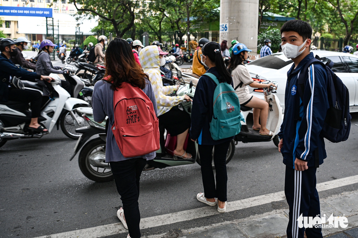 Một nhóm sinh viên cắt ngang dòng phương tiện trên đường Xuân Thủy để đi bộ sang đường - Ảnh: HỒNG QUANG