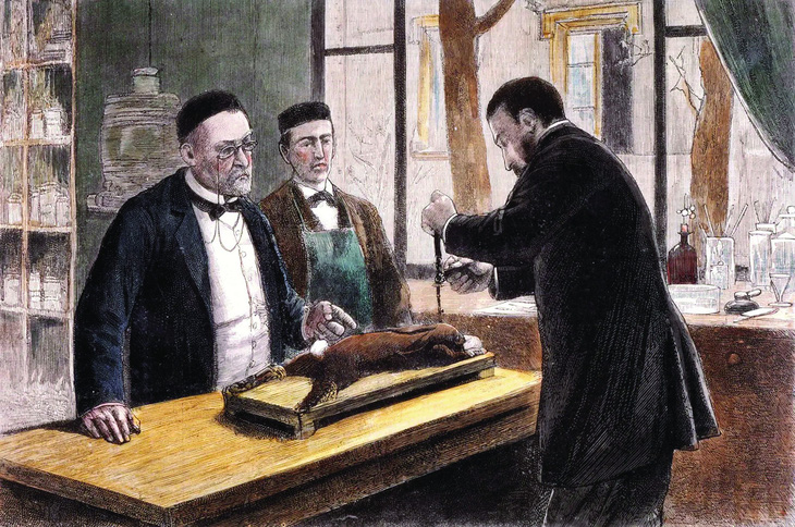Louis Pasteur (trái) quan sát một đồng nghiệp mổ mẫu vật trong quá trình nghiên cứu vắc xin phòng bệnh dại. Tranh khắc gỗ khoảng năm 1885. Nguồn: Britannica