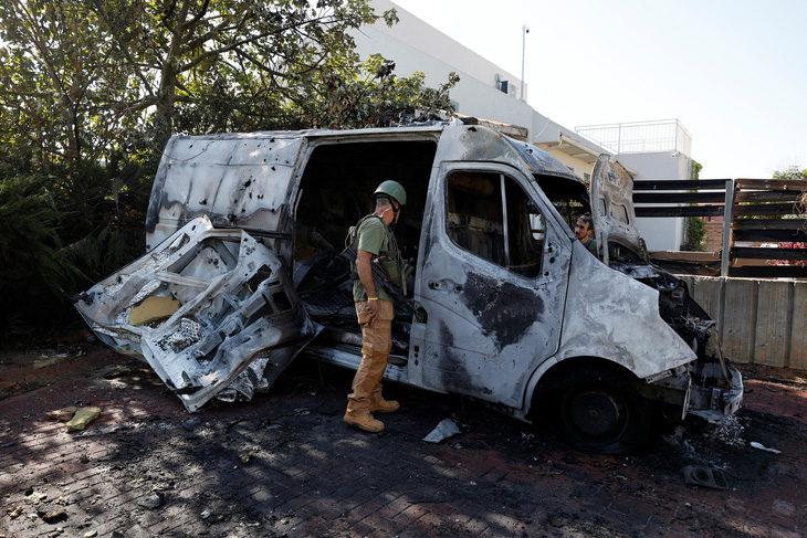 Nhân viên an ninh tại miền nam Israel kiểm tra một chiếc ô tô bị trúng rocket từ Dải Gaza trong ngày 1-12 - Ảnh: REUTERS