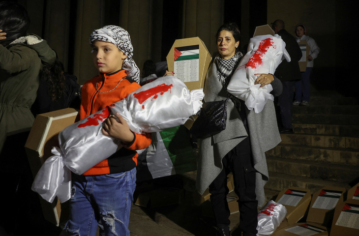 Những người biểu tình ôm thi thể giả được bọc kín và quan tài giả trong cuộc biểu tình yêu cầu ngừng bắn ngay lập tức và vĩnh viễn ở Dải Gaza tại Beirut, Lebanon, ngày 8-12 - Ảnh: REUTERS
