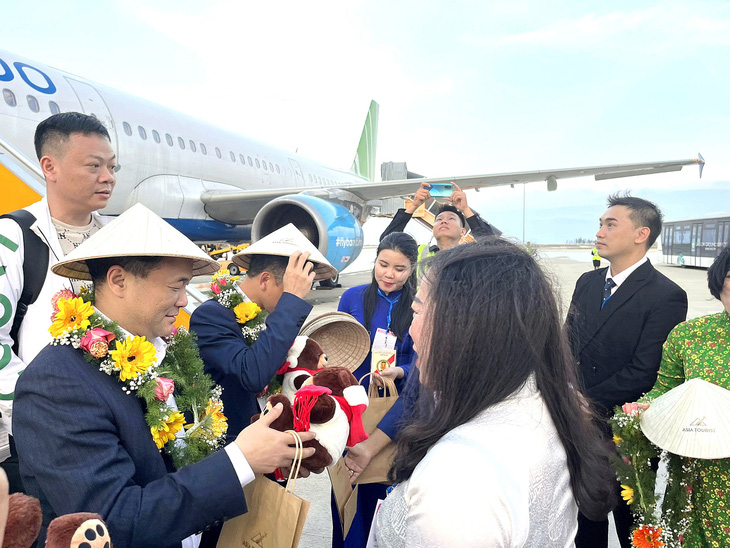 Khách Trung Quốc nhận hoa chào mừng du lịch Nha Trang tại sân bay quốc tế Cam Ranh (Khánh Hòa) - Ảnh: THỤC NGHI