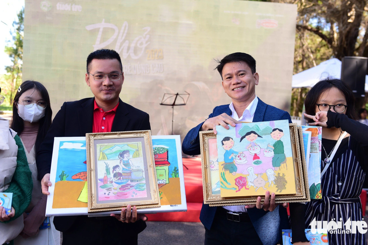 Ông Nguyễn Đức Mẫn (trái), đại diện Acecook nhận các bức tranh trẻ em vẽ trong sự kiện phở cộng đồng tại Đà Lạt ngày 10-12 - Ảnh: DUYÊN PHAN
