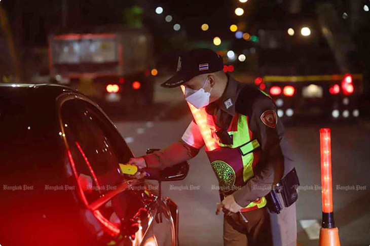 Một cảnh sát kiểm tra nồng độ cồn của tài xế bằng máy đo hơi thở tại trạm kiểm soát ven đường tháng trước  - Ảnh: Nutthawat Wichieanbut
