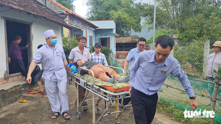 Bác sĩ cùng nhân viên y tế Bệnh viện Bình Định đưa bà Lan ra xe cấp cứu, chở về bệnh viện để chữa bệnh cho bà - Ảnh: LÂM THIÊN