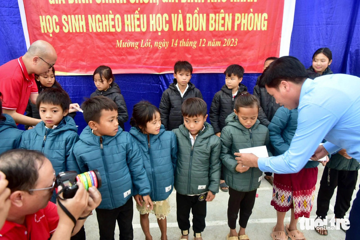 Ông Lường Văn Biên, chủ tịch UBND xã Mường Lói, và nhà báo Dương Đức Đà Trang (phó tổng thư ký tòa soạn báo Tuổi Trẻ - trái) trao quà cho các em học sinh - Ảnh: T.T.D.