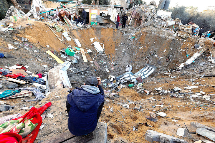 Một người Palestine ngồi nhìn vào nơi từng có những ngôi nhà nhưng đã bị phá hủy hoàn toàn trong các cuộc không kích của Israel tại thành phố Rafah, phía nam Dải Gaza, vào ngày 12-12 - Ảnh: REUTERS