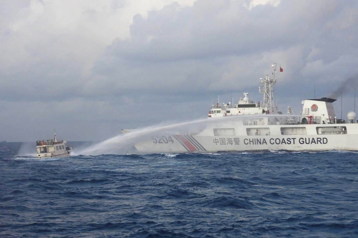 Tàu cảnh sát biển Trung Quốc (phải) phun vòi rồng vào một tàu tiếp tế của Philippines ở vùng tranh chấp tại Bãi Cỏ Mây ngày 10-12 - Ảnh: AFP