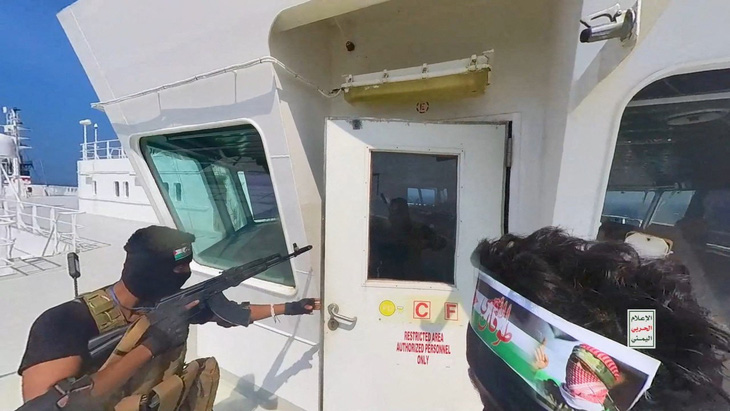 Chiến binh Houthi mở cửa buồng lái trên boong một con tàu ở Biển Đỏ - Ảnh: REUTERS