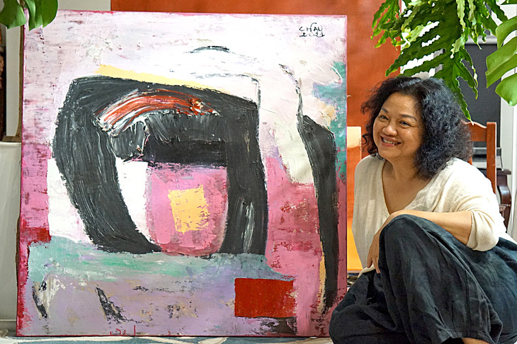 Nghệ sĩ Minh Châu bên một tác phẩm của bà tại xưởng vẽ đầy cây xanh - Ảnh: T.ĐIỂU