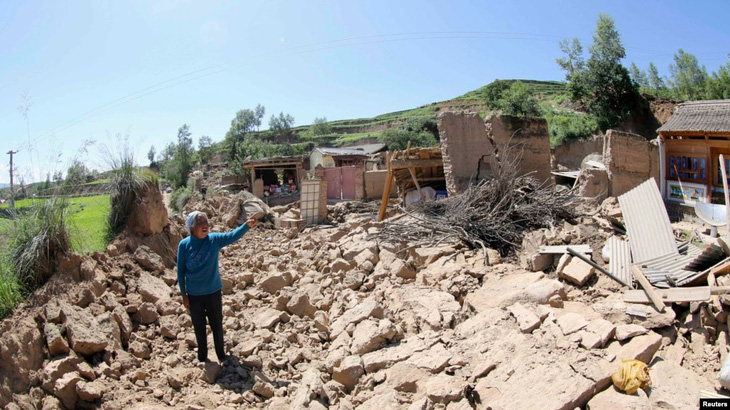 Người dân đứng trước ngôi nhà đổ nát trong trận động đất tấn công tỉnh Cam Túc, tây bắc Trung Quốc vào ngày 22-7-2013 - Ảnh: RFERL