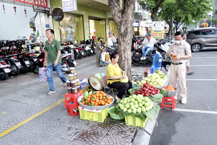 Các tiểu thương hàng rong vẫn chưa biết được phép bán ở khu vực nào sau khi có vạch kẻ vàng trên đường Phan Chu Trinh, quận 1, TP.HCM - Ảnh: T.T.D.