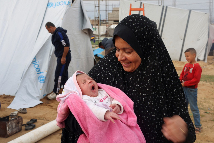 Bà Mervat Salha ôm cháu gái Mariam, được sinh ra trong cuộc xung đột Israel-Hamas, bên ngoài một cái lều dành cho những người mất nhà cửa do các cuộc không kích của Israel ở Rafah, nam Gaza ngày 17-2 - Ảnh: REUTERS