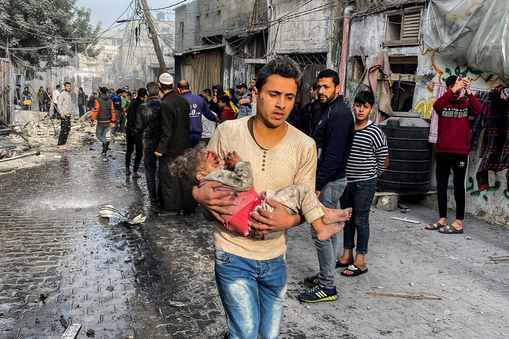 Một người Palestine bế em bé bị thương từ cuộc không kích của Israel ở thành phố Rafah, phía nam Dải Gaza - Ảnh: REUTERS