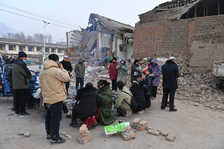 Người dân đốt lửa sưởi ấm bên ngoài những ngôi nhà bị sập sau động đất ở Cam Túc, Trung Quốc, ngày 19-12 - Ảnh: REUTERS