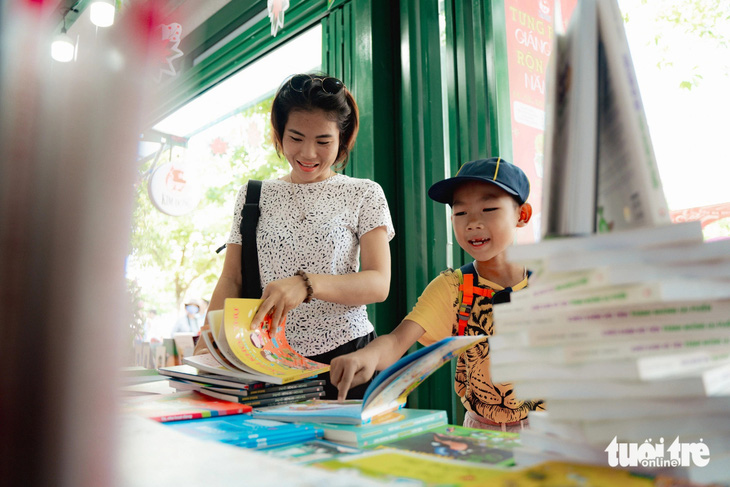 Một phụ huynh dẫn con trai tham quan và chọn mua sách tại gian hàng sách Kim Đồng - Ảnh: THANH HIỆP