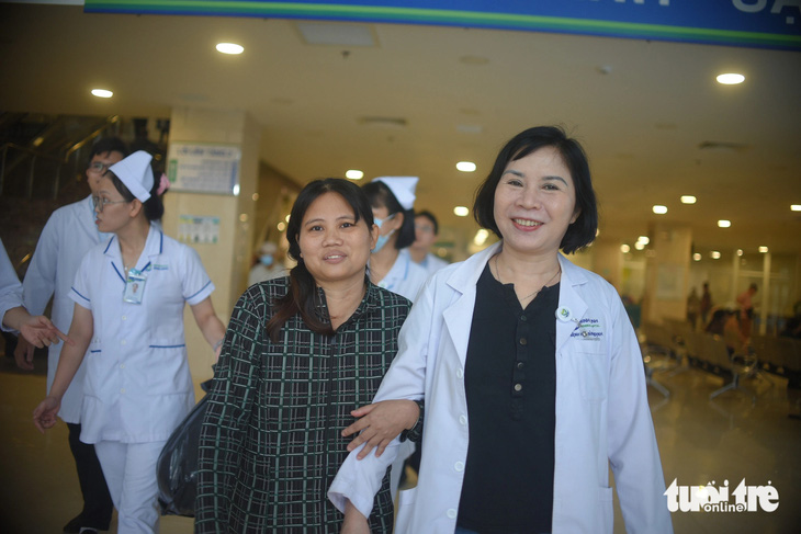 Bà Lan khoác tay trìu mến bác sĩ Bùi Thị Phương Anh (người đã trực tiếp chữa trị cho bà) trong lúc ra xe chuẩn bị về nhà - Ảnh: LÂM THIÊN