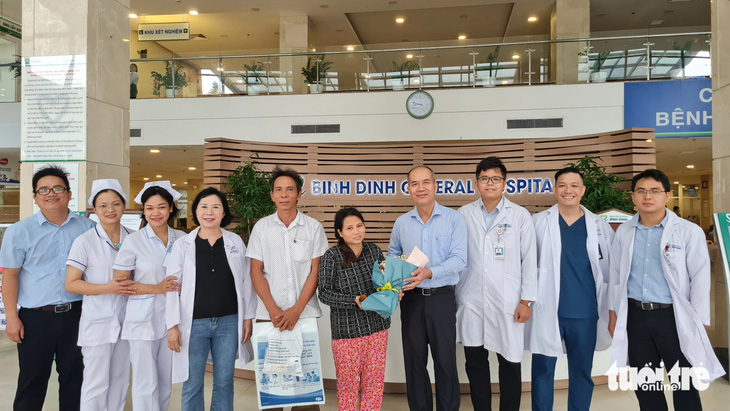 Lãnh đạo, y bác sĩ Bệnh viện Bình Định tặng hoa, chúc mừng bà Lan khỏe mạnh và trở về với gia đình - Ảnh: LÂM THIÊN