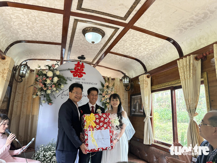 Ông Đặng Sỹ Mạnh - chủ tịch HĐTV Tổng công ty Đường sắt Việt Nam - tặng hoa cho cô dâu chú rể - Ảnh: LÊ ANH TUẤN