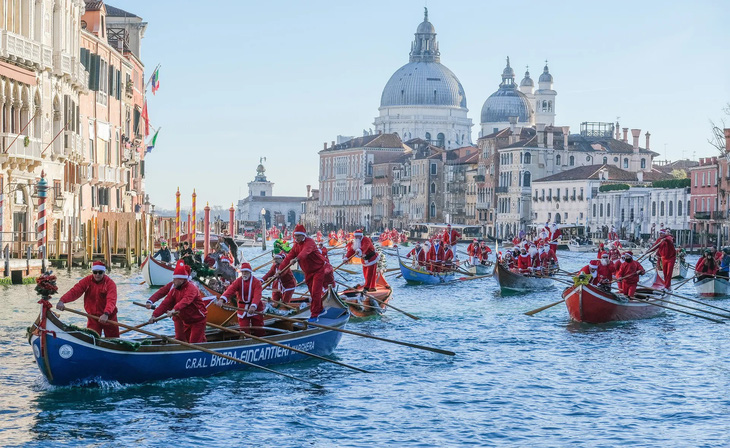 Một tuần trước ngày Giáng Sinh, ngày 17-12, các vận động viên trong trang phục ông già Noel đã tham gia giải đua thuyền trên kênh đào ở Venice, Ý. Hoạt động này đã được tổ chức thường niên trong nhiều năm. (Stefano Mazzola/Getty Images)