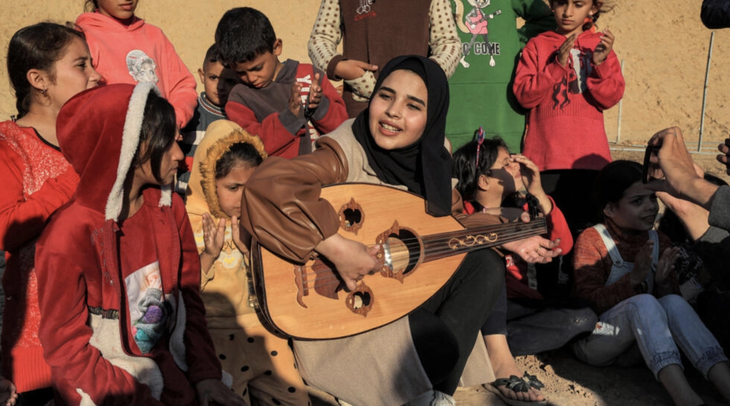 Nghệ sĩ Ruaa Hassouna chơi đàn oud và hát cho trẻ em Palestine nghe tại một khu trại tạm bợ hiện là nơi sinh sống của gần 2,4 triệu người dân Palestine - Ảnh: AFP