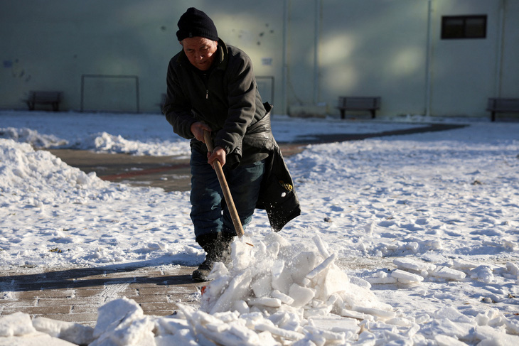 Nhân viên dọn tuyết tại một công viên ở Bắc Kinh, Trung Quốc hôm 22-12 - Ảnh: REUTERS