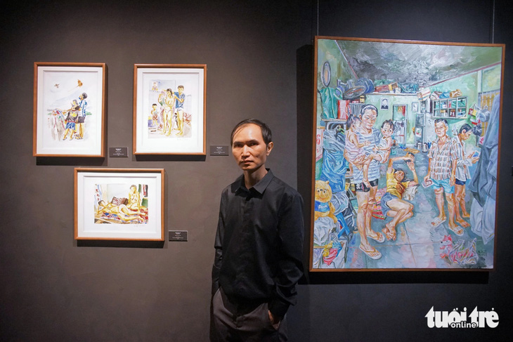 Họa sĩ Nguyễn Quốc Dũng bên các tác phẩm về người nhập cư tại triển lãm - Ảnh: H.VY