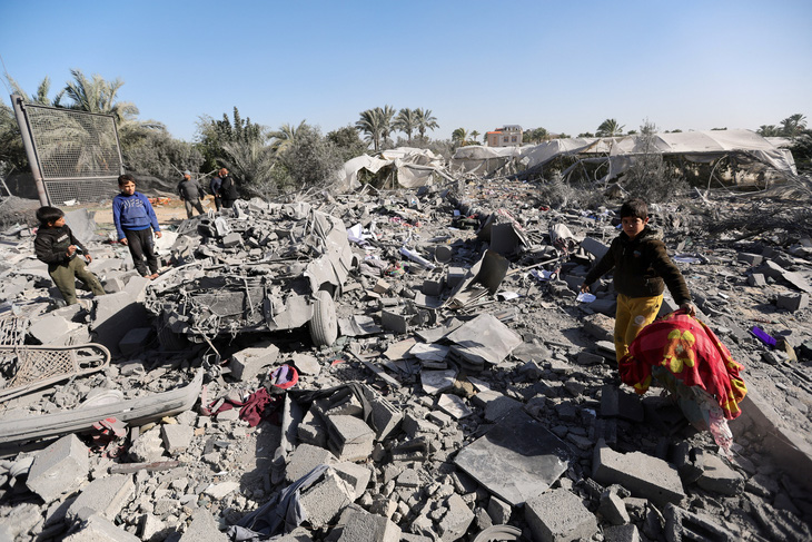 Người Palestine đứng nhìn đống đổ nát của ngôi nhà sau khi bị Israel tấn công ở Rafah, phía Nam Gaza, ngày 22-12 - Ảnh: REUTERS