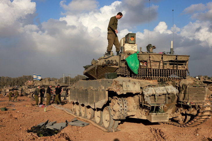 Binh sĩ Israel tập trung quanh chiếc xe tăng gần biên giới với Dải Gaza ở miền nam Israel hôm 24-12 - Ảnh: AFP