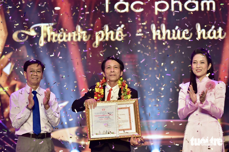 Ông Nguyễn Thọ Truyền (bìa trái), bà Nguyễn Thị Thanh Thúy trao giải nhất cho tác giả Trần Công Nghị - Ảnh: T.T.D.