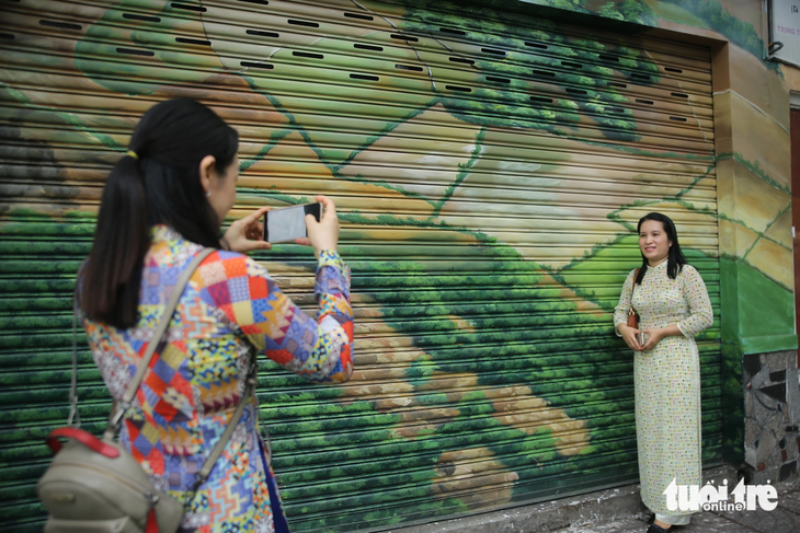 Người dân tới chụp ảnh kỷ niệm cùng bức tranh bích họa trên đường Võ Thị Sáu, quận 3, TP.HCM - Ảnh: MINH HÒA