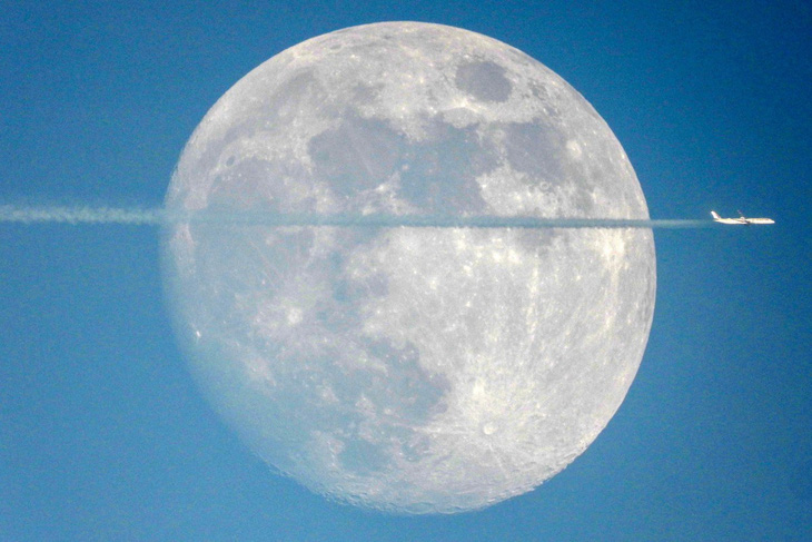 Khoảnh khắc máy bay thương mại bay qua Mặt trăng đang nhô lên trên bầu trời thành phố Kuwait được nhiếp ảnh gia ghi lại hôm 25-11 - Ảnh: AFP