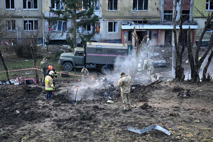 Quân nhân Ukraine đang xem xét phần còn lại của một tên lửa trong sân của một tòa nhà bị hư hại từ cuộc tấn công của Nga vào Liviv, miền tây Ukraine, ảnh chụp ngày 29-12 - Ảnh: AFP