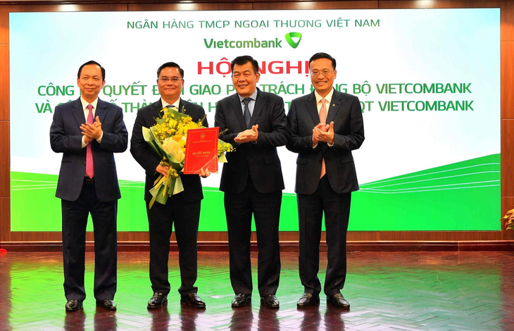 Ông Đào Minh Tú - Phó Thống đốc thường trực NHNN Việt Nam (ngoài cùng bên trái) - trao quyết định và tặng hoa chúc mừng ông Nguyễn Thanh Tùng - Ảnh: VCB