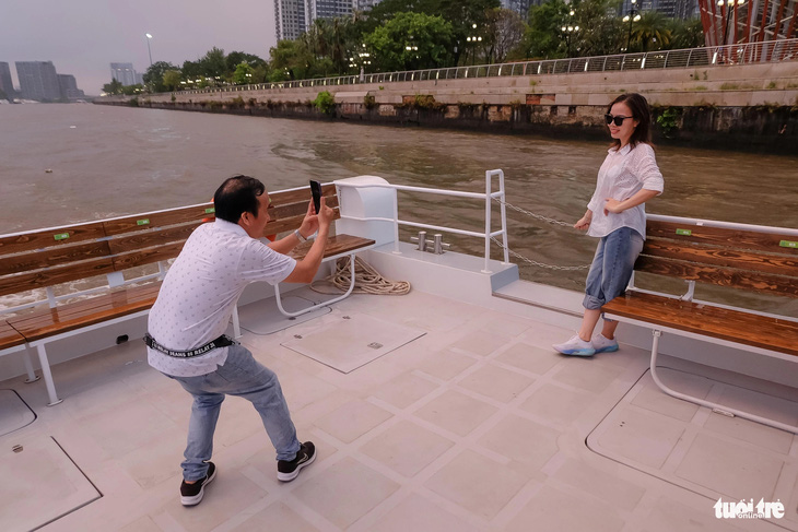 Vợ chồng chị Vũ Thị Tuyết chụp ảnh, check-in trên tàu buýt sông hai tầng - Ảnh: PHƯƠNG NHI
