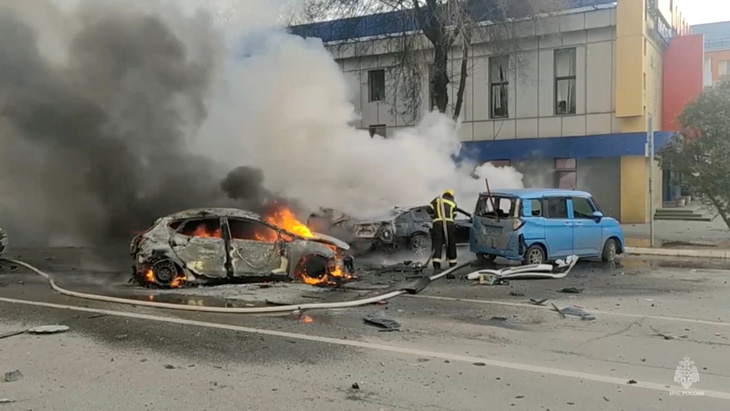 Lính cứu hỏa dập lửa trên chiếc ô tô bốc cháy sau vụ pháo kích của Ukraine ở Belgorod, Nga, ngày 30-12 - Ảnh: REUTERS