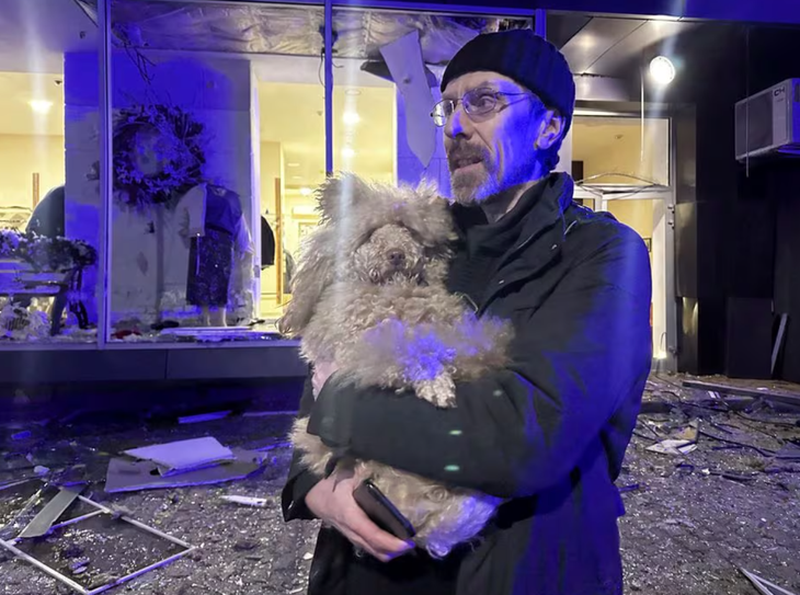 Một người dân địa phương ôm chú chó của mình trước hiện trường vụ tấn công của Nga vào thành phố Kharkov, Ukraine ngày 30-12 - Ảnh: REUTERS 