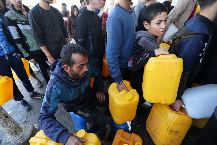 Người dân Palestine xếp hàng nhận nước ở thành phố Khan Yunis ngày 4-12 trong lúc Israel đang đánh xuống miền nam Gaza - Ảnh: REUTERS