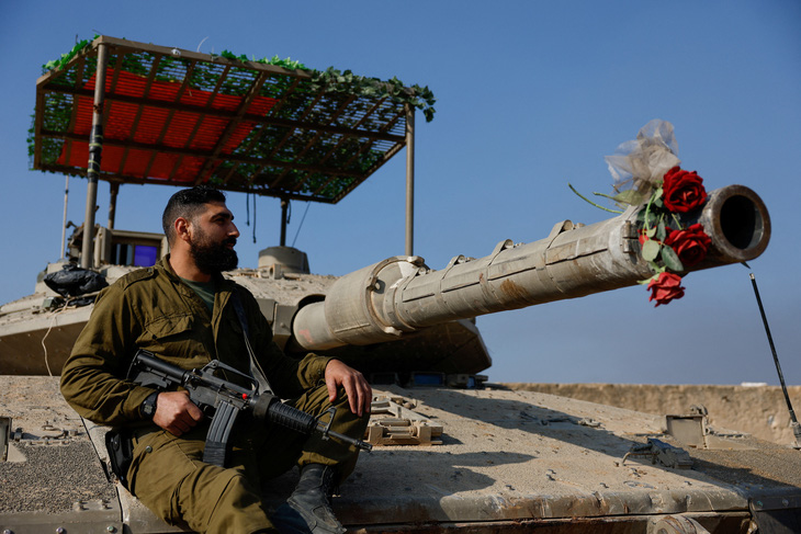 Binh sĩ Israel ngồi trên chiếc xe tăng được trang trí bằng hoa giả, sau khi lệnh ngừng bắn tạm thời giữa Israel và Hamas hết hạn, ngày 1-12 - Ảnh: REUTERS