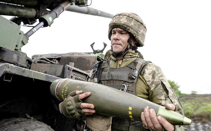 Một quân nhân Ukraine cầm đầu đạn cho pháo tự hành Caesar tại thị trấn Avdiivka, vùng Donetsk - Ảnh: REUTERS