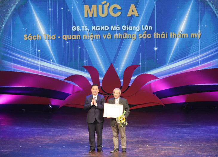 Trưởng Ban Tuyên giáo Trung ương Nguyễn Trọng Nghĩa (trái) trao tặng thưởng mức A cho ông Mã Giang Lân - Ảnh: TRẦN HOANG
